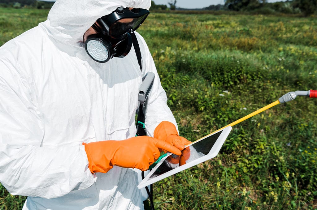 Mensch in schutzanzug auf einem feld mit tablet und